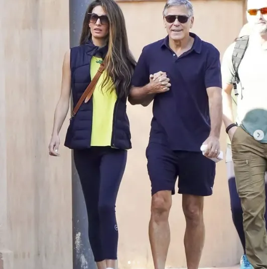 Amal Clooney and George Clooney walking on their English estate, showcasing her fitness routine and wellness lifestyle.
