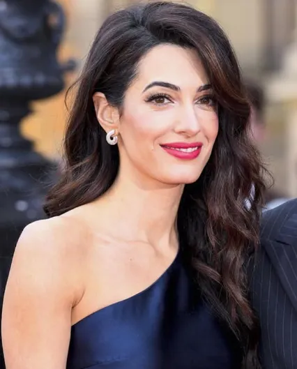 Amal Clooney applying hydrating serum in a luxurious bathroom, emphasizing her skincare and beauty routine for glowing skin.